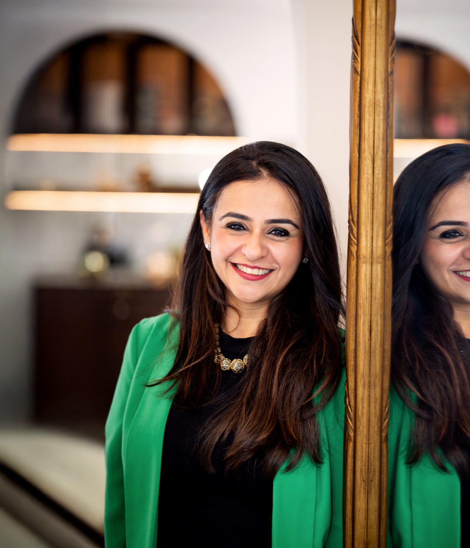 Ritika smiling beside an antique gold mirror