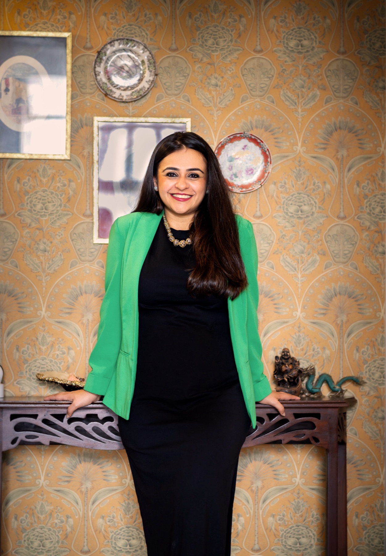 Ritika standing in front of patterned wallpaper