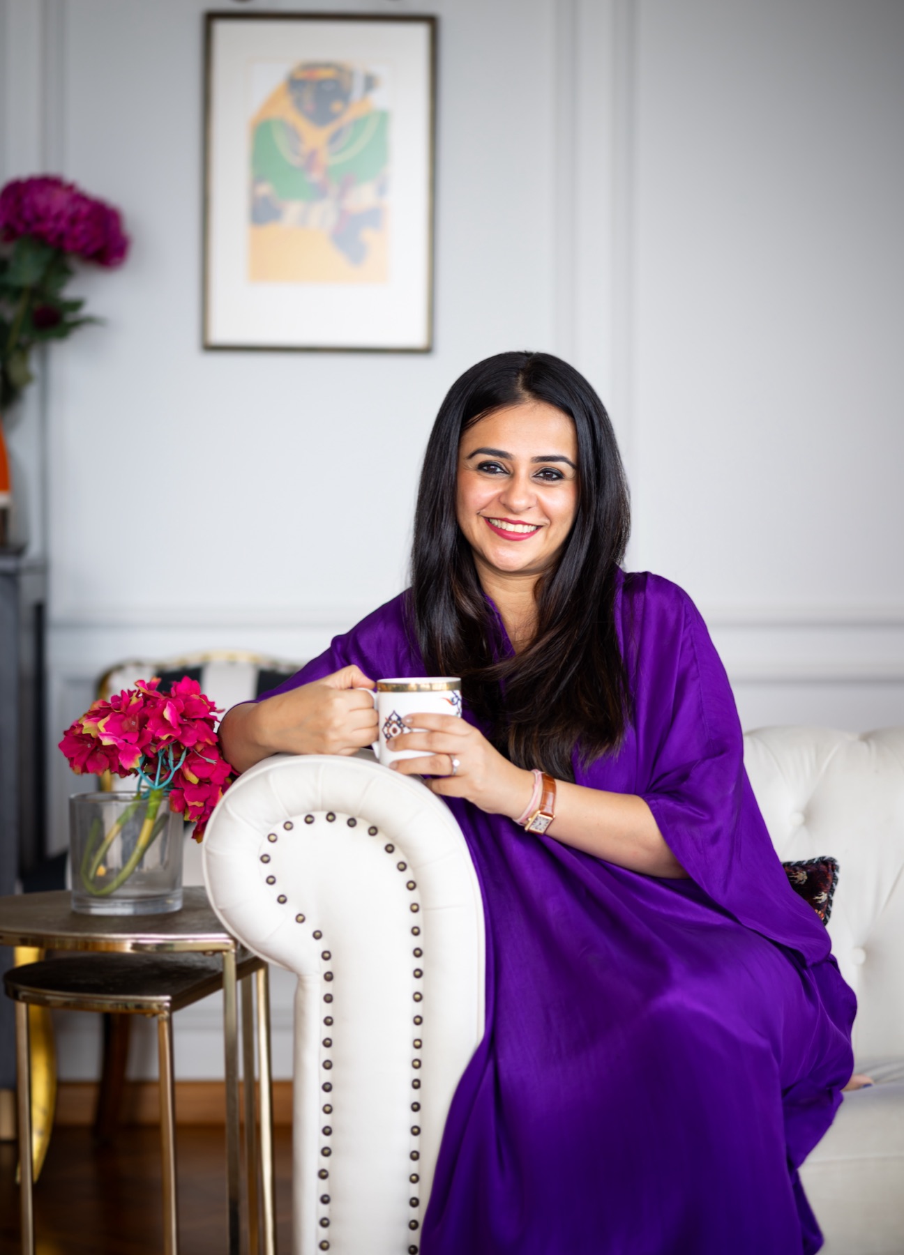 Ritika with a cup of tea on a white sofa